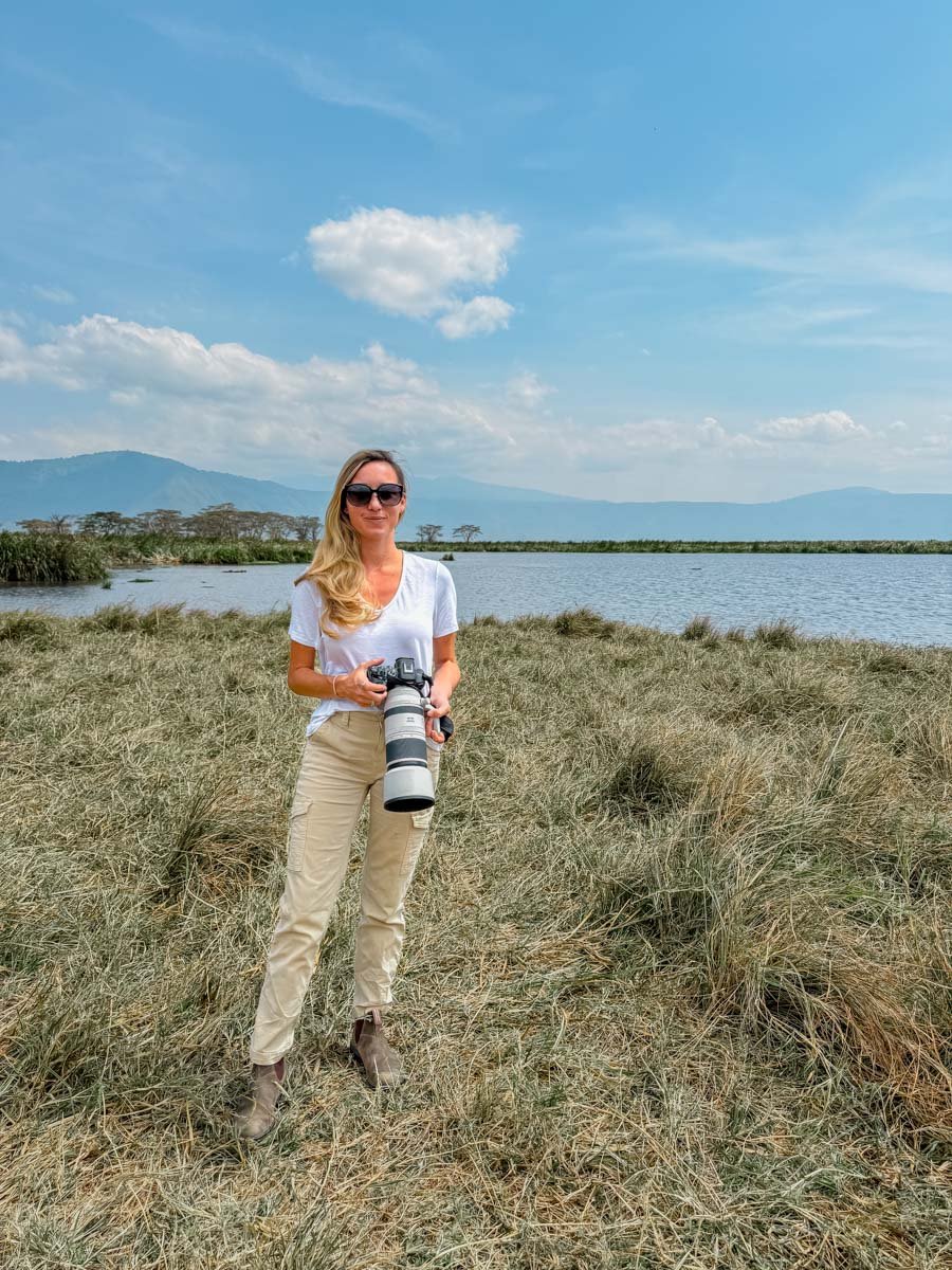Sam at Ngorongoro Crater by the lake wearing a white cotton tee and long pants.